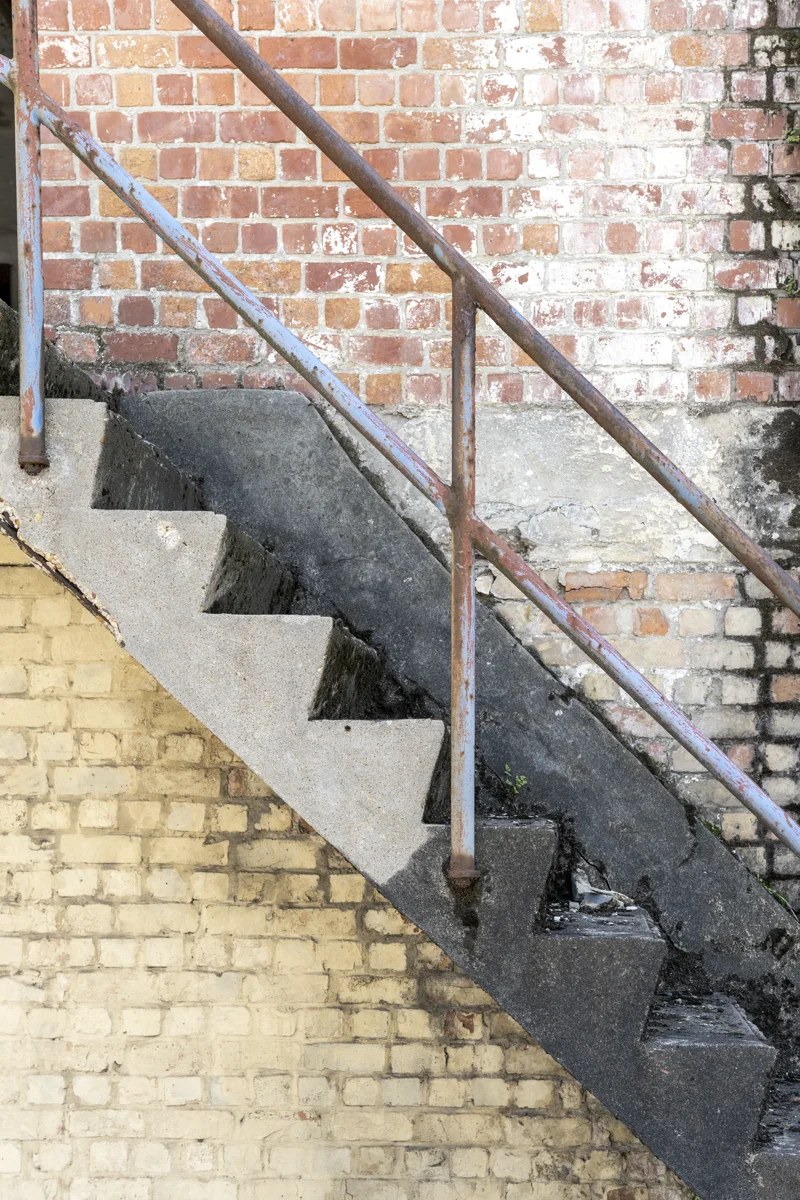 Escalier béton et murs de brique encrassés, typiques des supports résistants traités